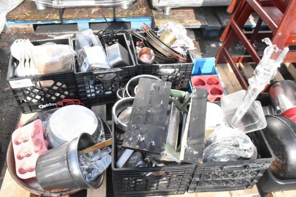 Pallet lot of various kitchen items, including baking pans, skillets, utensils, and crates. Mixed condition, possibly useful for resale.