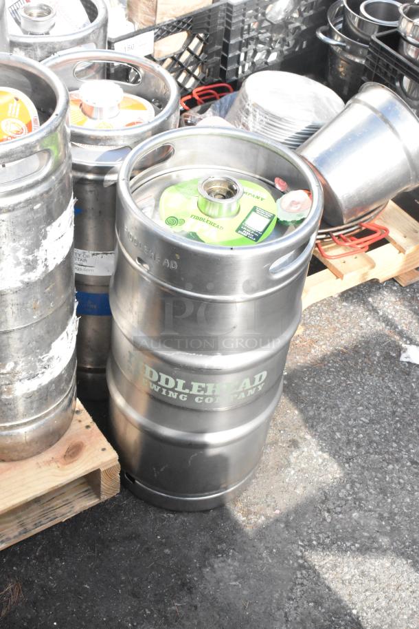 12 mixed kegs, some branded "Fiddlehead Brewing Company," in various conditions on a wooden pallet.