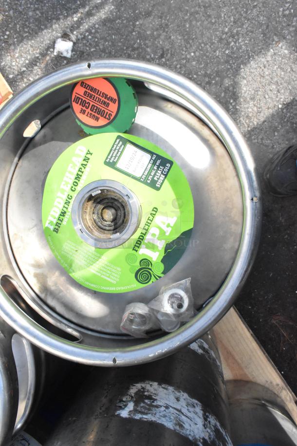 Stainless steel keg with Fiddlehead Brewing Company IPA label, includes condition markings. Auction includes 12 kegs, bid multiplies by 12.