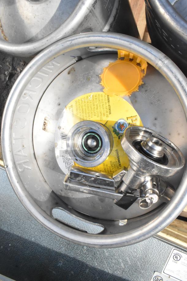 12 various metal kegs with connectors, showing wear. "MICROSTAR" branding and a safety label are visible.