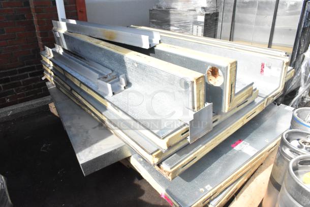 Metal walk-in box panels on a pallet, showing insulation edges and steel exterior, in fair condition with visible wear.