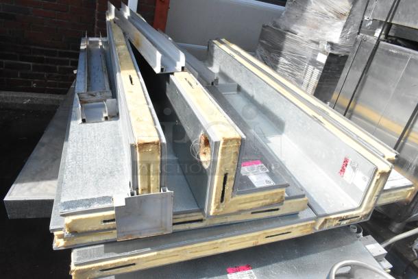 Stacked metal panels for a walk-in box, showing insulation and labeling. Panels appear slightly worn. Labels indicate assembly instructions.