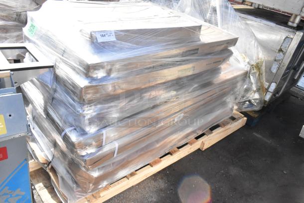 Stack of 10 brand new scratch and dent tabletops wrapped in plastic on a wooden pallet. Visible labels indicate item number FEB26-100 and quantity of 184.