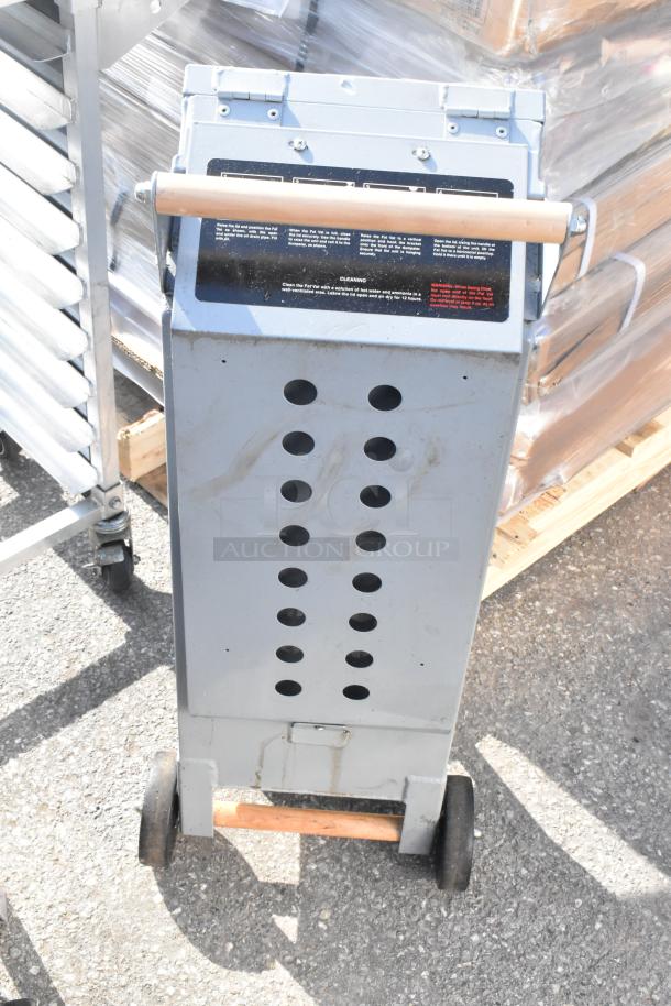 Commercial fat vat oil shuttle, gray with perforated design, wooden handle, on wheels; cleaning instructions visible on label.