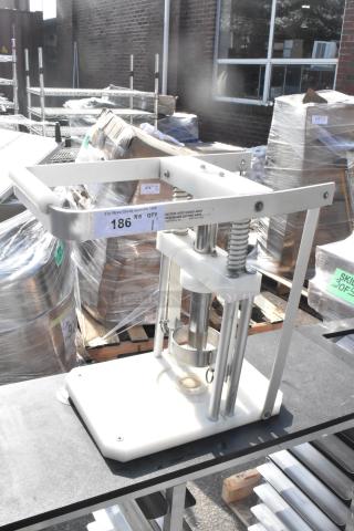Industrial-grade countertop pineapple corer, metal frame, manual operation, visible safety caution label, new condition.