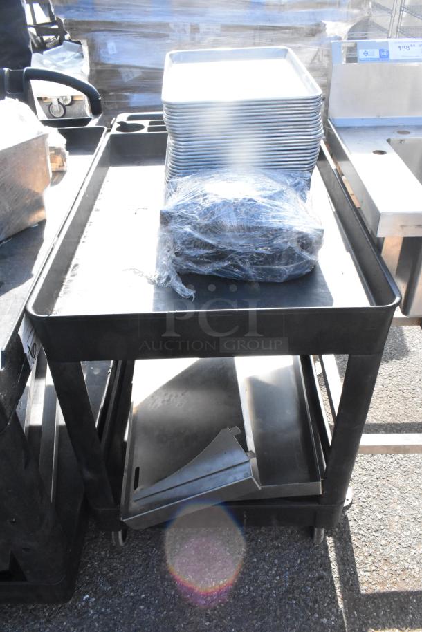 Poly 2-tier cart with commercial casters, includes plastic-wrapped contents and stacked trays on top shelf, in good condition.