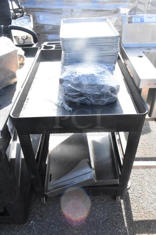 Poly 2-tier cart with commercial casters, includes plastic-wrapped contents and stacked trays on top shelf, in good condition.
