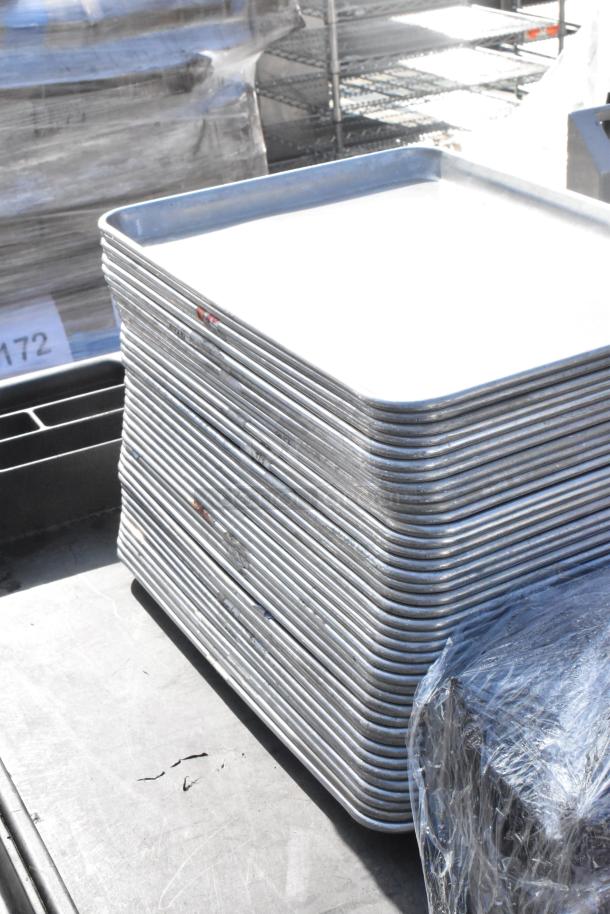 Poly 2 Tier Cart with stack of metal trays on commercial casters. Trays appear in used condition; cart is partially visible.