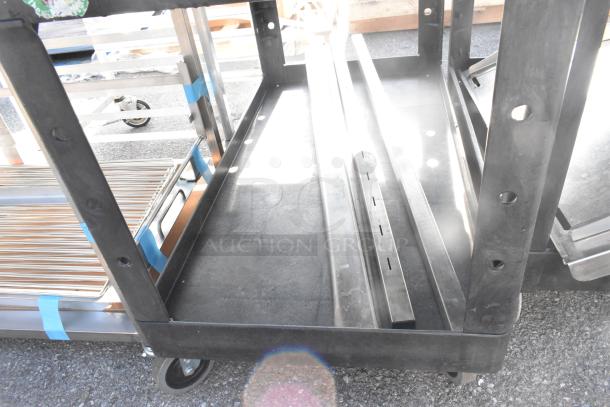 Rubbermaid Brute Poly 2 Tier Cart with contents on commercial casters, black, shows light use, suitable for industrial transport.