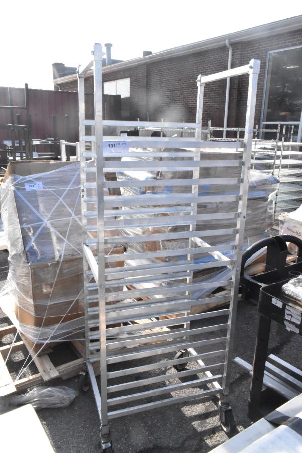 Commercial pan transport rack with multiple shelves on heavy-duty casters, metal construction, used condition. Tags show quantity info.