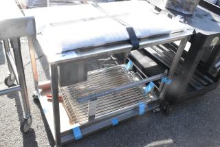 Stainless steel table on commercial casters, two-tier design, includes grate shelf. Condition: Used. Auction tag: Lot 192.