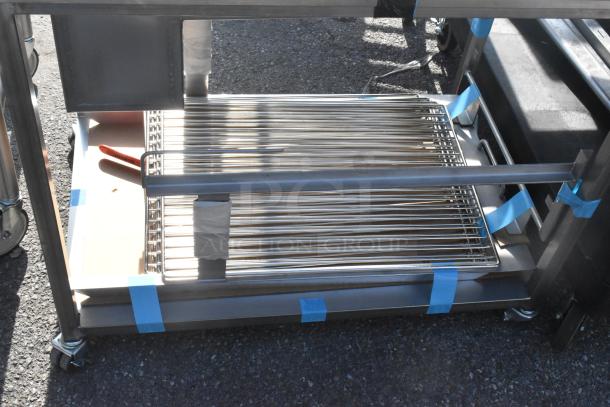 Stainless steel table on commercial casters with metal shelving and blue tape accents, ideal for heavy-duty use.