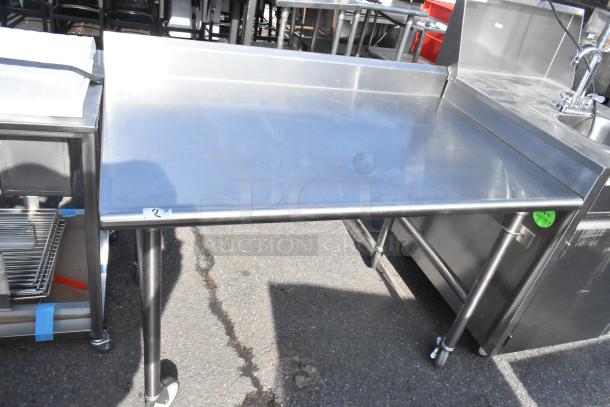 Stainless steel table on commercial casters, featuring a smooth top and rear backsplash, suitable for industrial use.