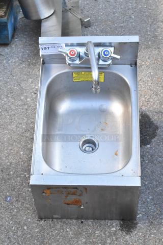 Stainless steel commercial single bay sink without legs, with dual faucet handles and visible usage marks.