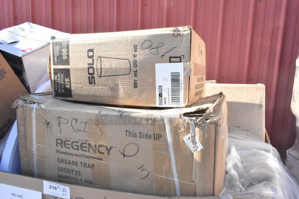 Boxes of auction items including Regency grease trap, Solo cups, slight damage visible. New scratch and dent condition.