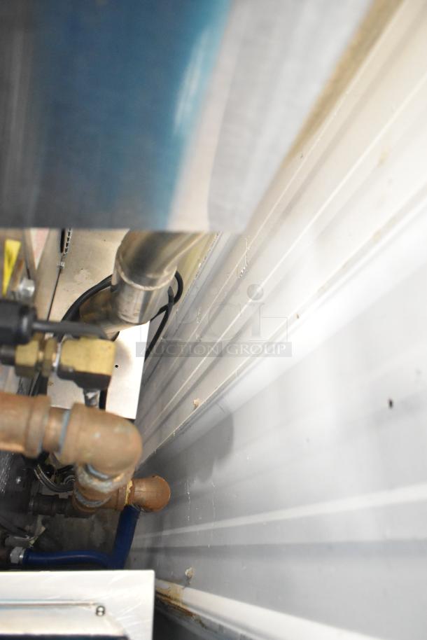 Close-up of gas connection pipes and fittings behind a Blodgett HV-100G convection oven.