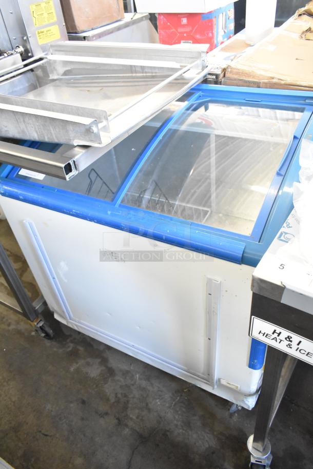 XS-208 chest freezer merchandiser on commercial casters, with a clear sliding lid, blue trim, and 115 volts, 1 phase power.