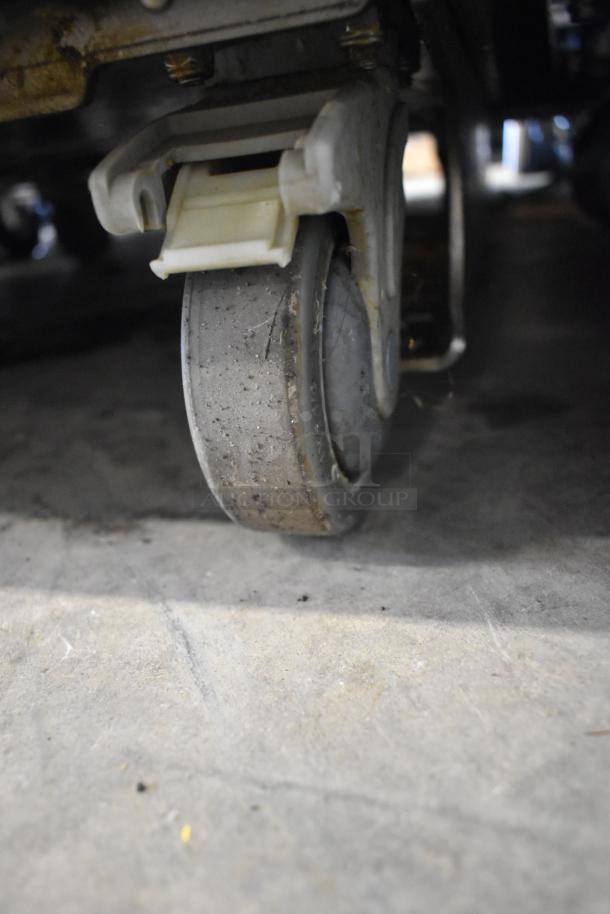 Close-up of a commercial caster on a JBT 2ND-GEN-MFJ-HE citrus juicer. Caster shows wear, indicating regular use.