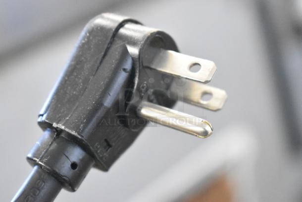 Close-up of a standard three-prong plug connected to the 2022 Amana RCS10TS Commercial Microwave Oven, 120 Volts, 1 Phase.