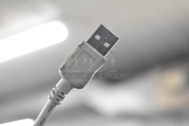 USB cable with visible wear on the connector, showing a small amount of dirt. Background is blurred.