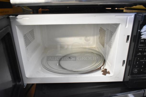 Mainstays P100N30AP-S3B1 countertop microwave oven, black, open door view showing interior condition with glass turntable.