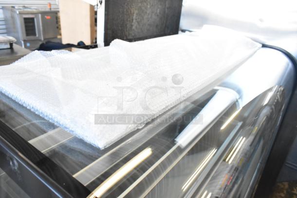 Brand new Avantco 193BC48HCB 48" curved glass bakery display case with bubble wrap, black finish, commercial casters, 110-120V.