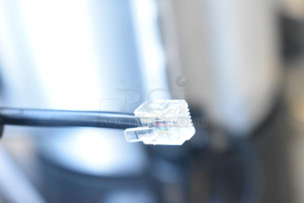 Close-up of a black cable with a clear connector attached, likely part of the Avantco 177EG24N scale setup.