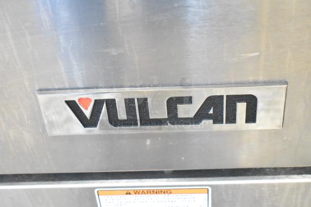 Alt Text: Vulcan 24S-4BN commercial range badge, showing stainless steel finish with brand logo and warning label below.