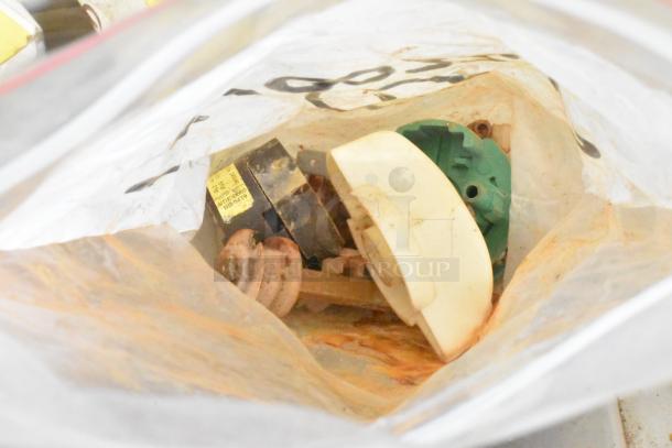 Two bins of various Taylor ice cream machine parts, including augers. Parts are used, visible wear, with inventory tags.