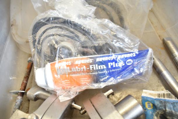 Two bins of Taylor ice cream machine parts, including augers and lubricant. Some parts show wear, enhancing maintenance needs.