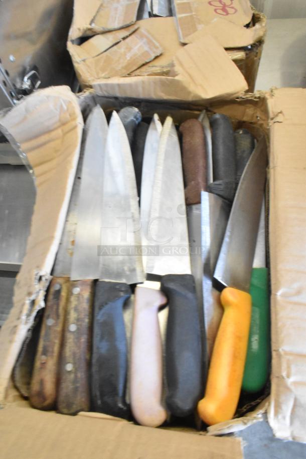 A box containing 100 sharpened stainless steel knives, featuring various handles. Includes chef knives. Box is worn.