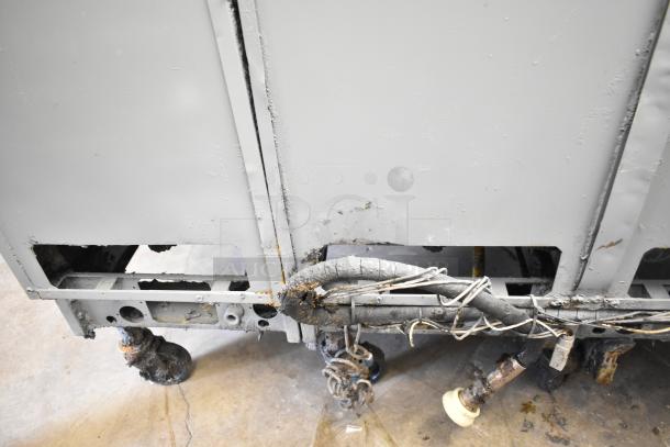 Pitco Frialator stainless steel 4-bay deep fat fryer. Natural gas-powered. Visible wear and rust on commercial casters. 122,000 BTU.