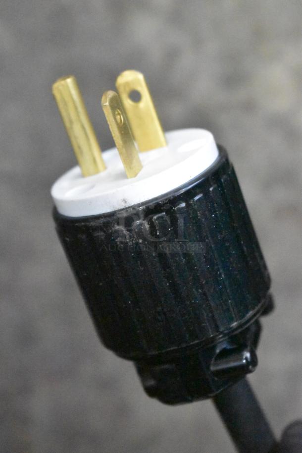 Close-up of a power plug from the ServIt 423HDM26SA 26" Heated Display Case, showing prongs and black casing.