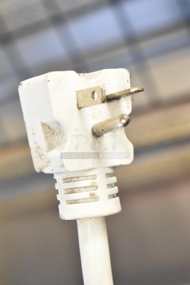Close-up of a white electrical plug for a Turbo Air TOM-50B air curtain merchandiser. Visible wear and markings.