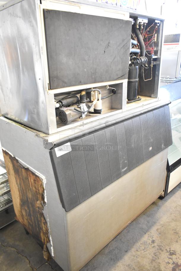 Hoshizaki KM-1301SWH commercial ice machine on bin, visible internal components, worn exterior, 208-230V, 1 phase.