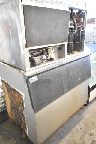 Hoshizaki KM-1301SWH commercial ice machine on bin, visible internal components, worn exterior, 208-230V, 1 phase.