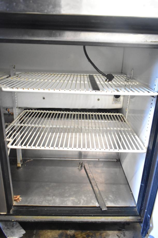 True TSSU-48-12 sandwich salad prep table interior showing wire shelving and power cord, used condition.