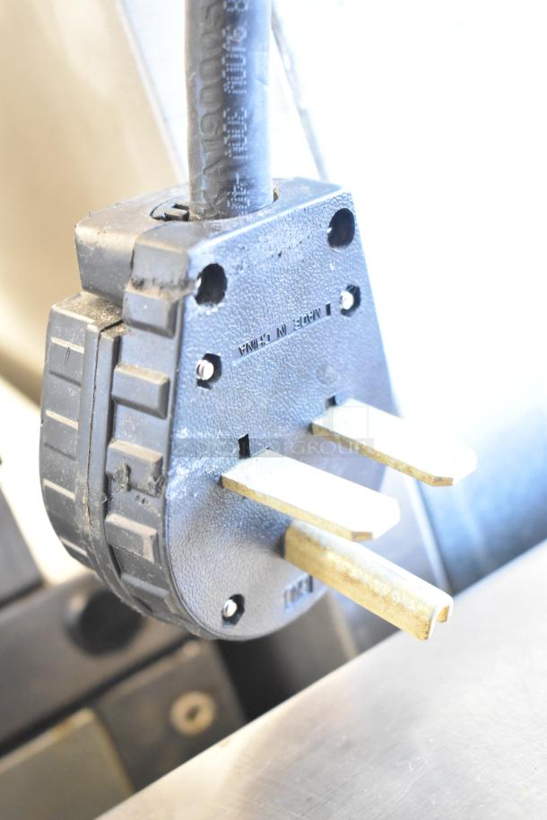 Close-up of a power plug connected to a 2023 Ice-O-Matic CIM1446HR6 Commercial Ice Machine, showing prongs and plug markings.