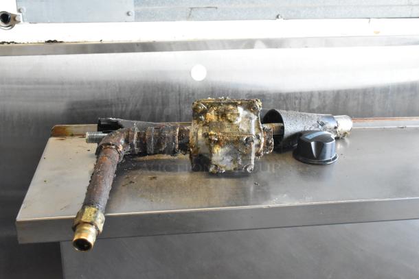 Rusty gas component with pipe and knob set on a metallic surface, part of a Garland SunFire commercial range.