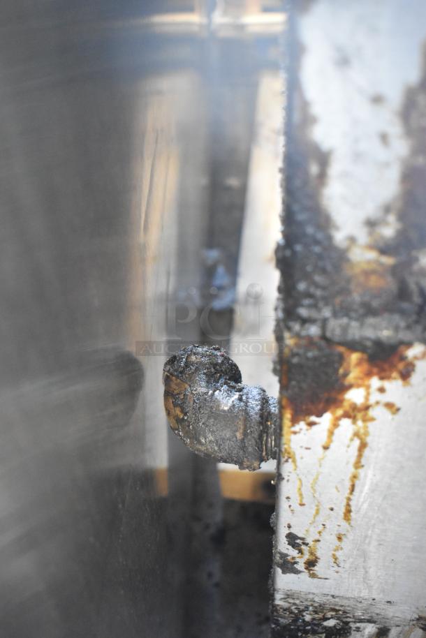 Garland SunFire 10 burner range with gas hookup detail, showing wear and residue on the metal surface.