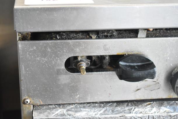 Garland SunFire commercial gas range, close-up showing control knob and wear, includes 10 burners, 2 ovens, over shelf, backsplash.