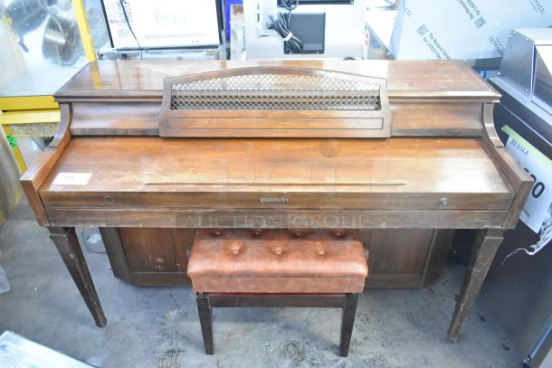 Baldwin piano with matching piano bench, made of wood with some visible wear; features Baldwin logo on front.