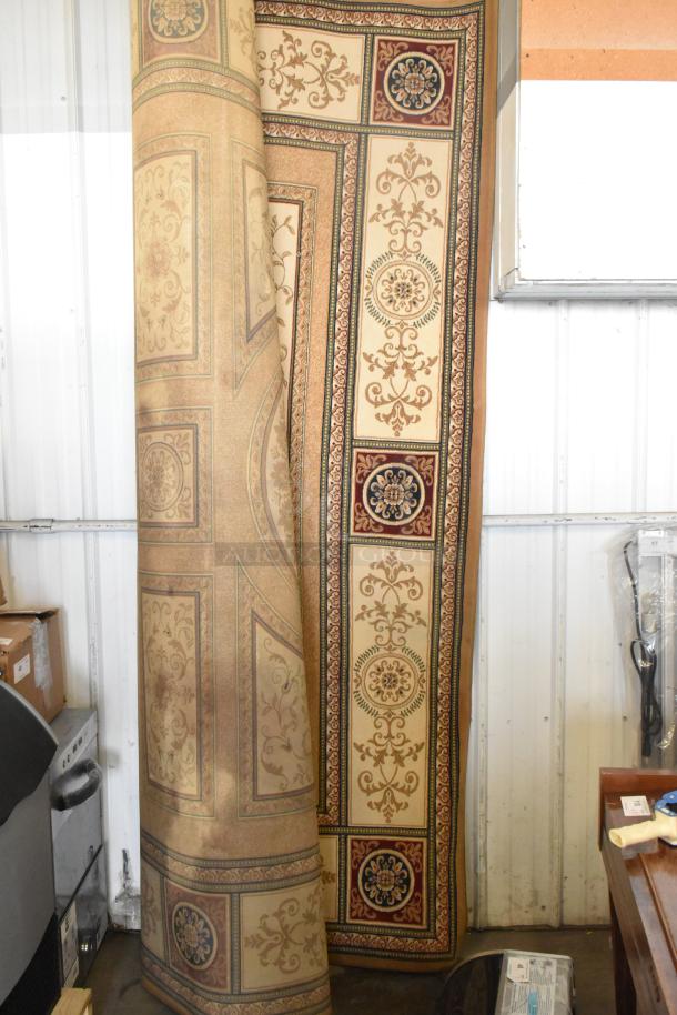 Ornate beige and burgundy rug with floral patterns, rolled partially, in good condition, suitable for auction display.