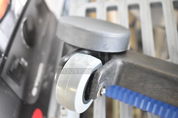 Brand new vacuum attachment, minor scratches and dents, gray and black plastic, blue brush bristles, wheel detail visible.