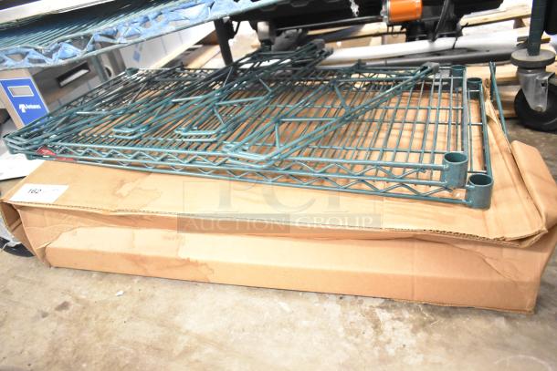 Seven items including four green finish brackets, two Metro green finish wire shelves, and a Metro GS1836K3 grid shelf, on a cardboard box.