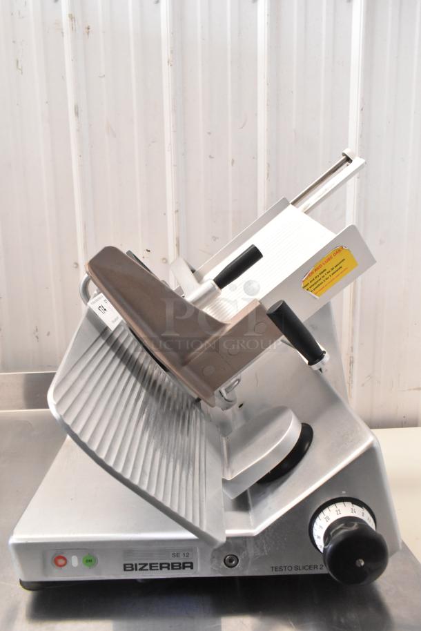 Bizerba commercial countertop meat slicer, model SE 12, 120 volts, 1 phase, with adjustable slicing knob and visible caution sticker.