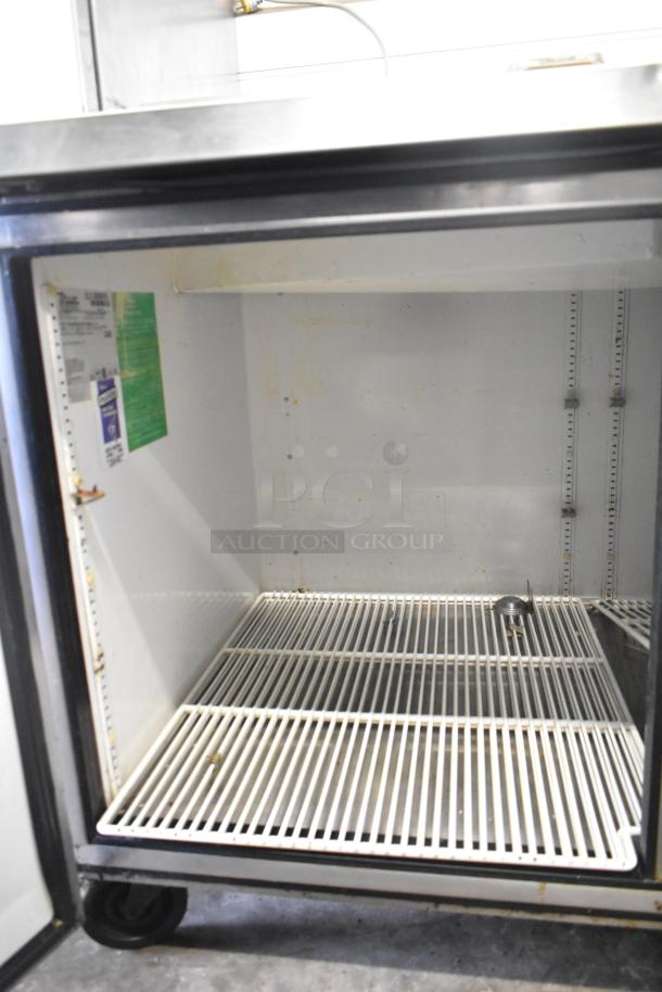 True TPP-67 commercial pizza prep table with shelves, on casters. Visible interior, voltage 115V, 1 phase.