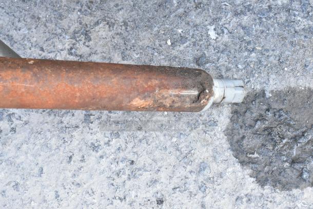 Close-up of a rusted leg on a commercial right side dirty dish table, indicating wear and exposure to elements.