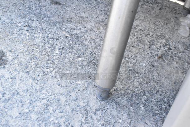 Stainless steel leg of CMA AH-2 commercial dishwasher on textured floor; durable construction visible.