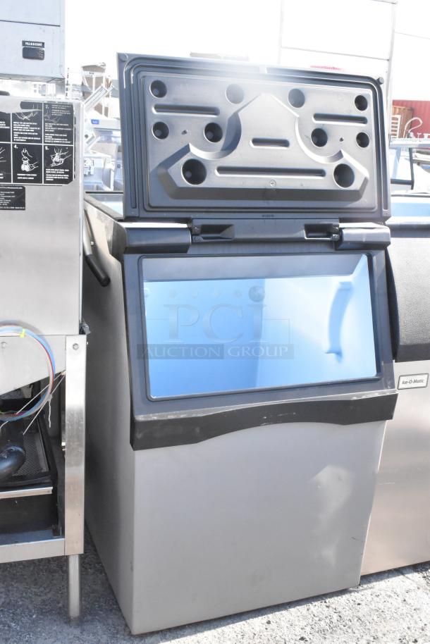 Commercial Ice Bin with a black lid, stainless steel body, and visible Ice-O-Matic branding. Appears in good condition.